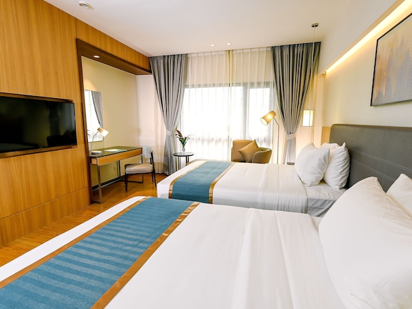 Hotelzimmer mit zwei Betten, Schreibtisch, Fernseher und Stuhl.