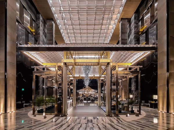Weitläufige Hotellobby mit großen Säulen und einer gerasterten Decke.