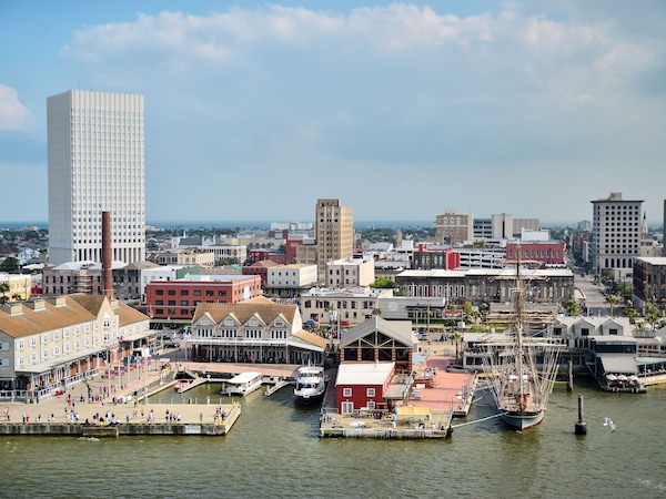 Stadt am Wasser mit modernem Hochhaus, historischen Gebäuden und Bootsanleger.