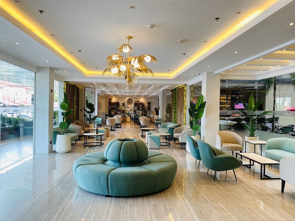Helle Hotellobby mit modernem Kronleuchter und gemütlichen Sitzbereichen.