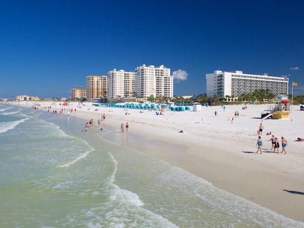 Belebter Strand mit Rettungsturm und Hochhäusern im Hintergrund.