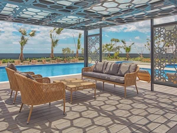 Poolbereich mit Korbmöbeln, Sofa und Meerblick.